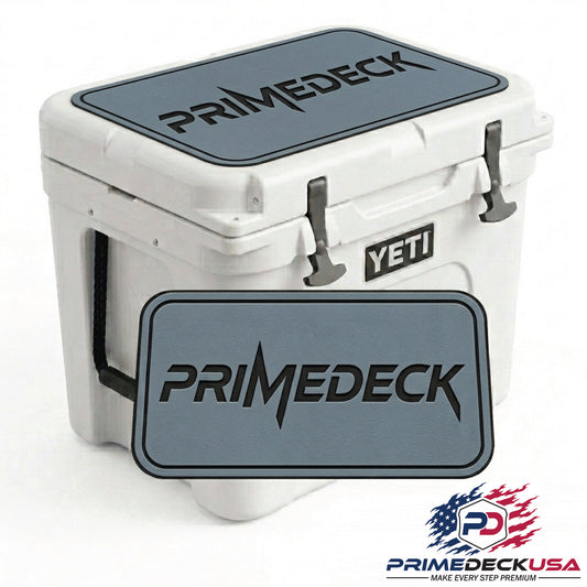 A white YETI cooler with a dark gray PRIMEDECK branded lid decal shown on top and as a larger front overlay. The YETI brand badge is visible on the side of the cooler.