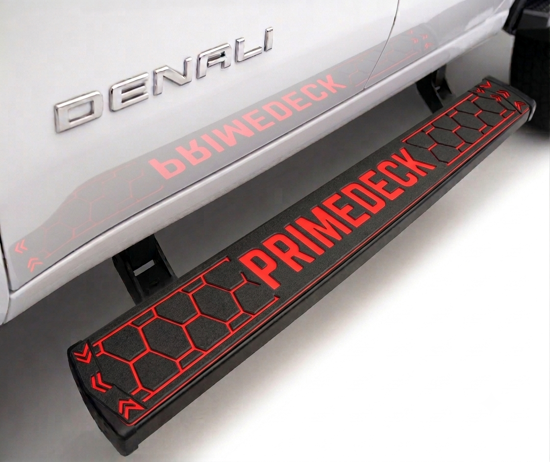 A black and red PrimeDeck vehicle side step bar mounted under a white Denali truck, with the words PRIMEDECK and DENUALI visible.